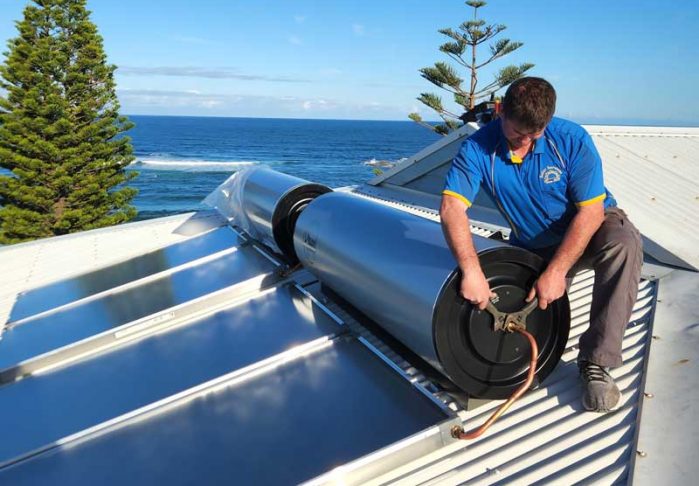 Man fixing solar panel on rooftop — Solar Power Services in Bateau Bay, NSW